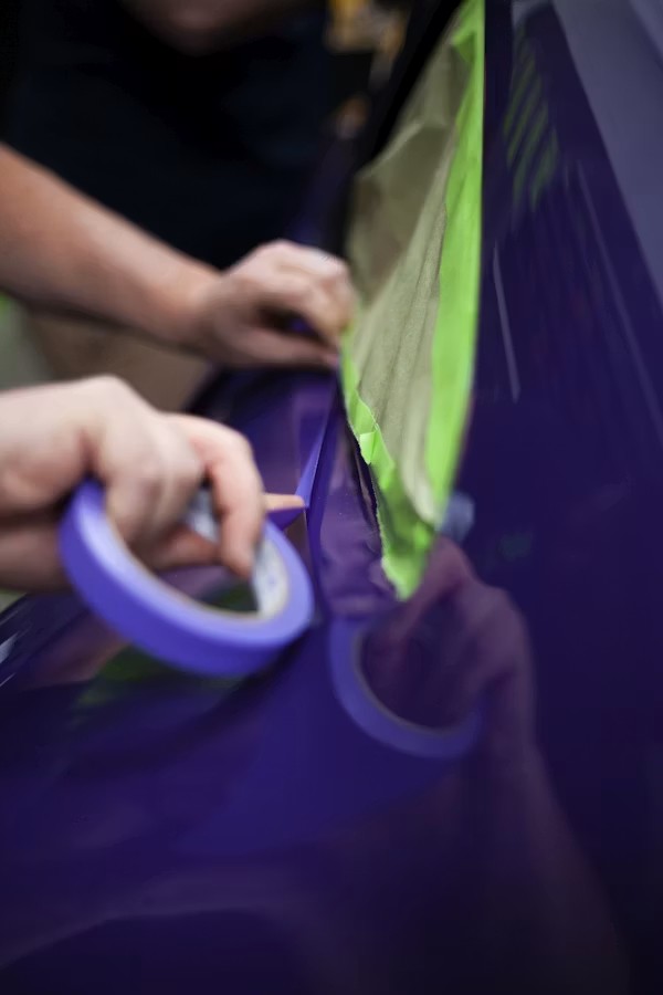 Auto body technician color-matching paint on a repaired vehicle panel