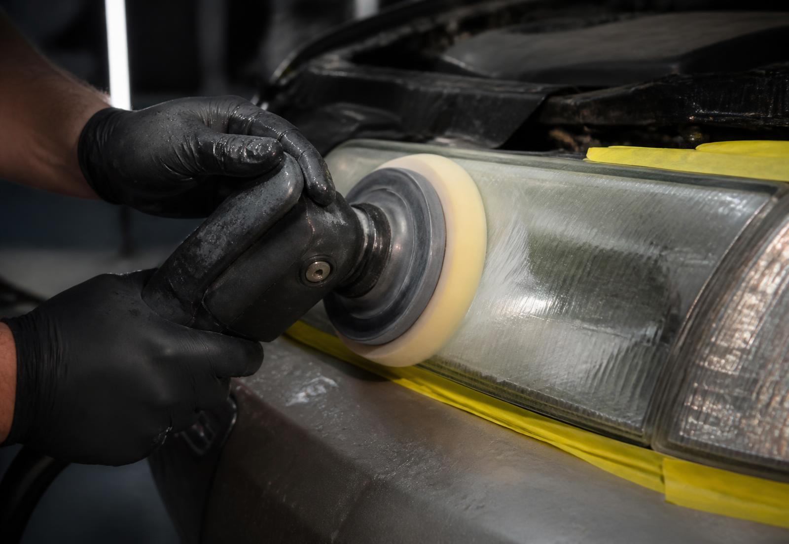 Technician machine polishing a yellowed headlight lens during headlamp restoration in California
