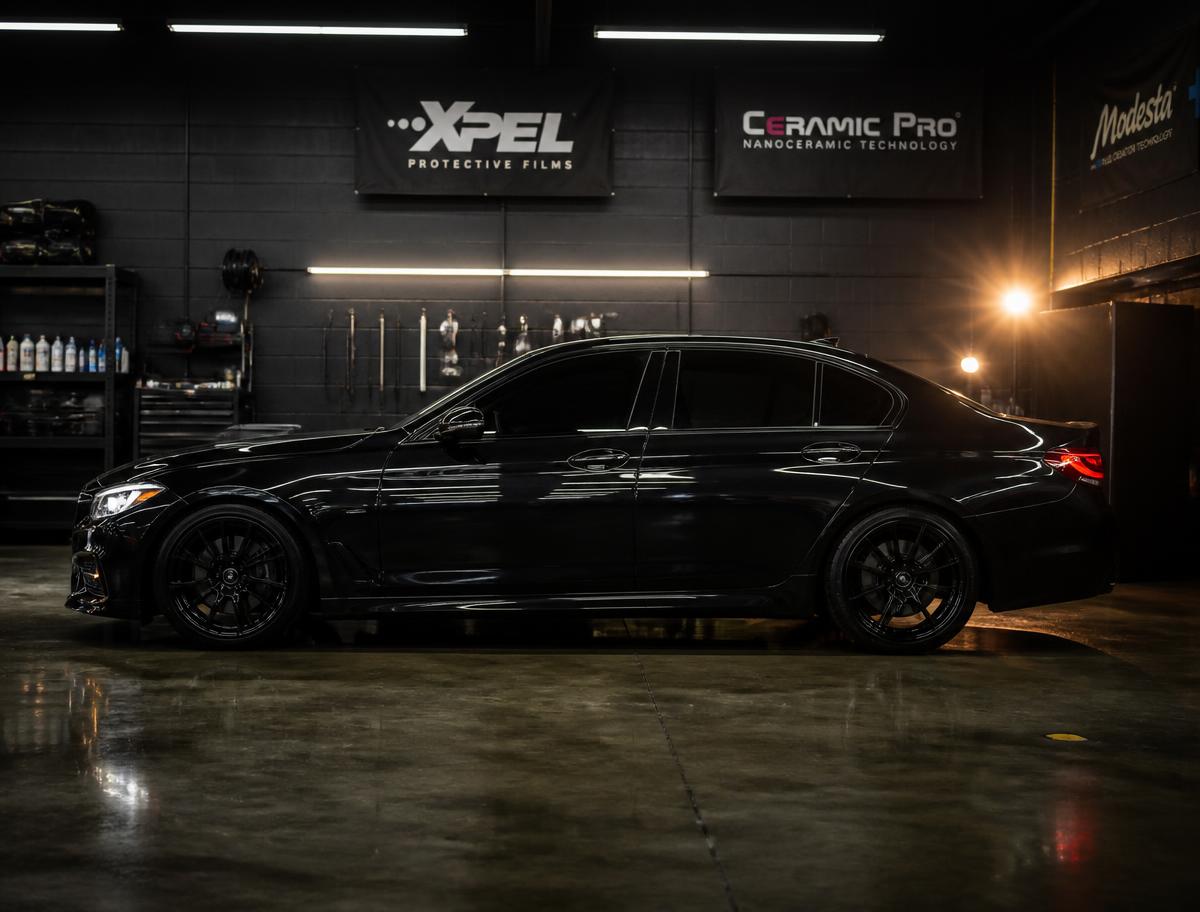 Dark sedan with freshly installed ceramic window tint at a California auto shop